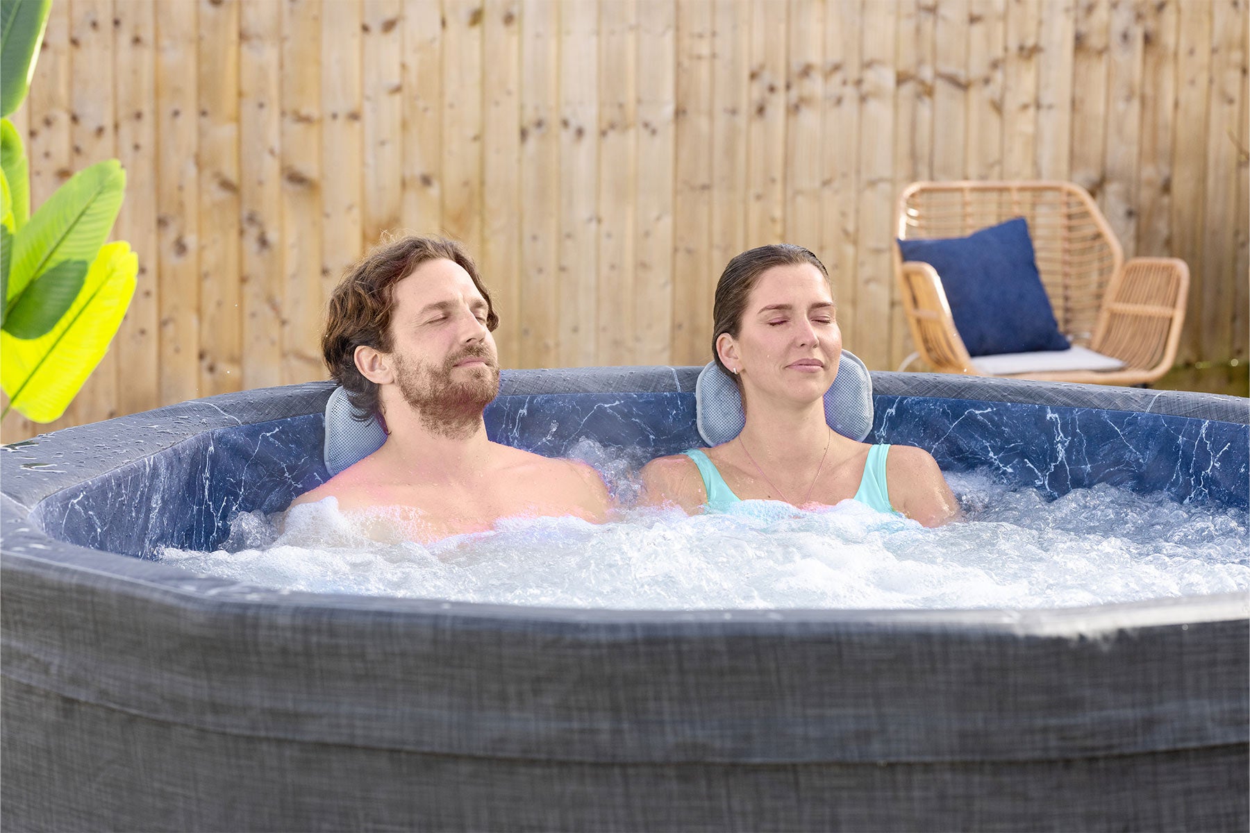 Two people relaxing in a Lay-Z-Spa hot tub with included pillows outdoors